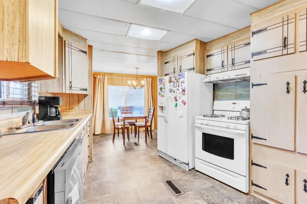 a kitchen with stainless steel appliances a stove a refrigerator and a dining table with wooden floor