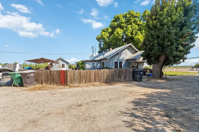 a backyard of a house with large trees and wooden fence