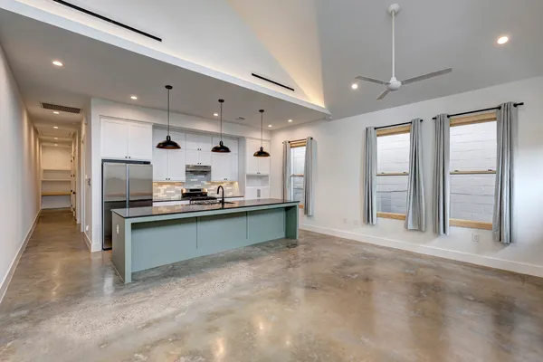 a large kitchen with granite countertop a large counter top stainless steel appliances and cabinets