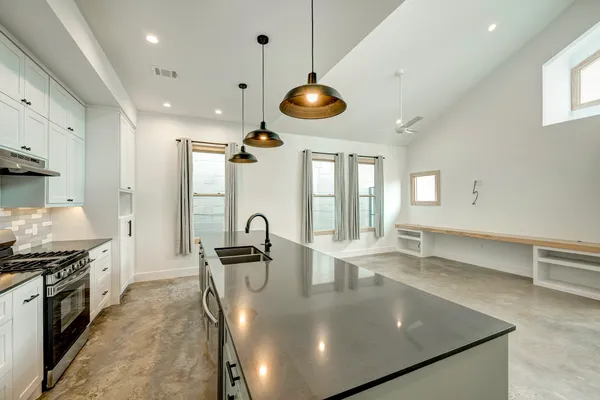 a kitchen with stainless steel appliances granite countertop a sink a stove and a wooden floors