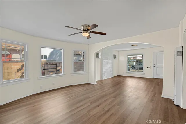 a view of an empty room with a window and wooden floor