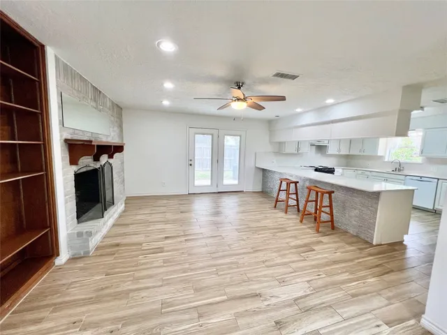 a large kitchen with stainless steel appliances granite countertop a stove a sink dishwasher and a refrigerator with wooden floor