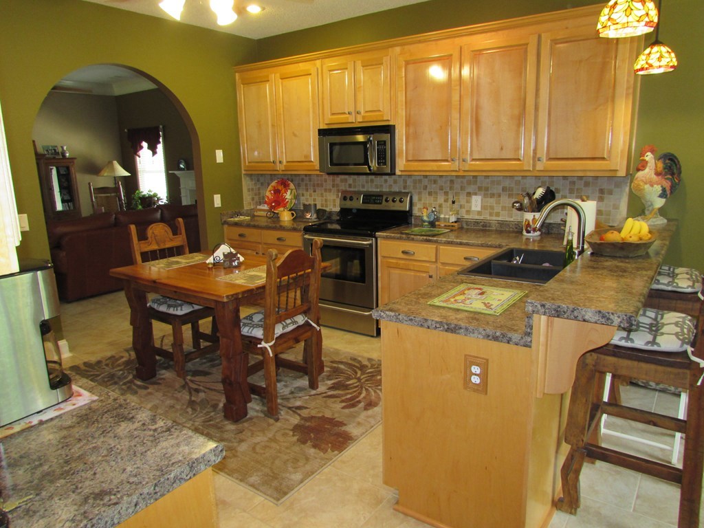 7440 Goodall Mill Road Macon, GA 31216 - Photo 10 of 33 a kitchen with a stove top oven a sink a dining table and chairs