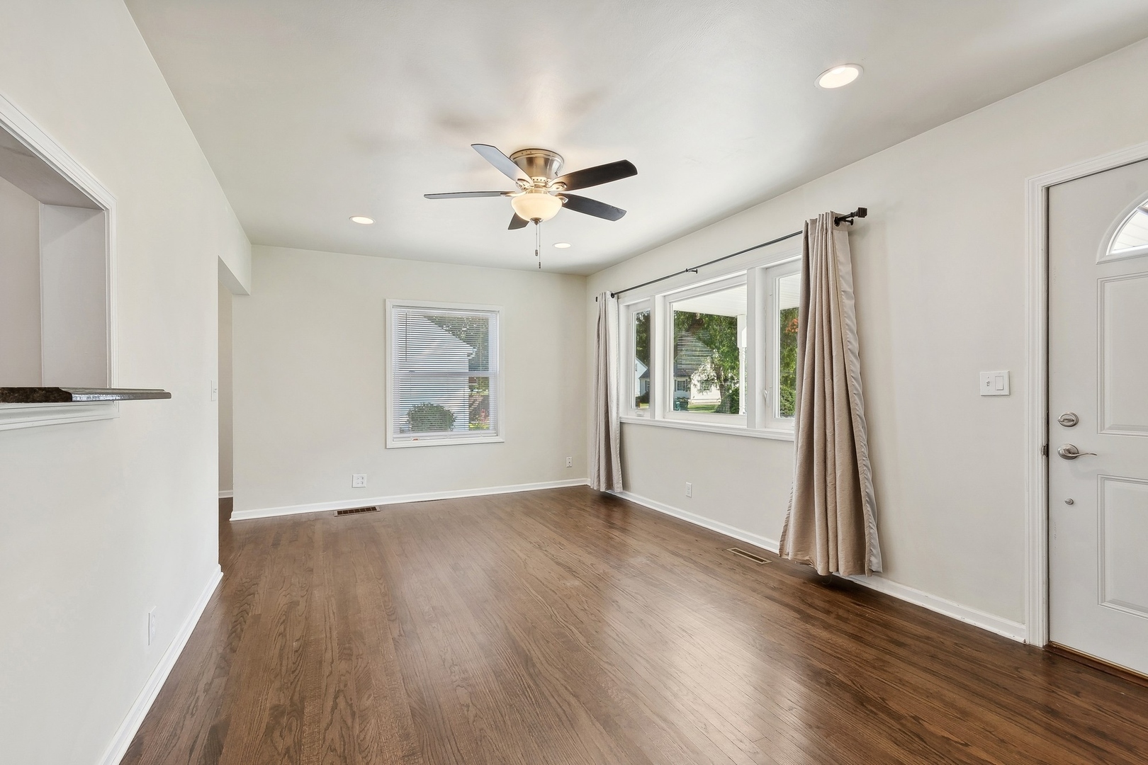 1513 Marquette Road Joliet, IL 60435 - Photo 2 of 16 an empty room with wooden floor chandelier fan and windows