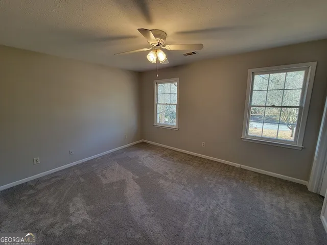 an empty room with windows and chandelier fan