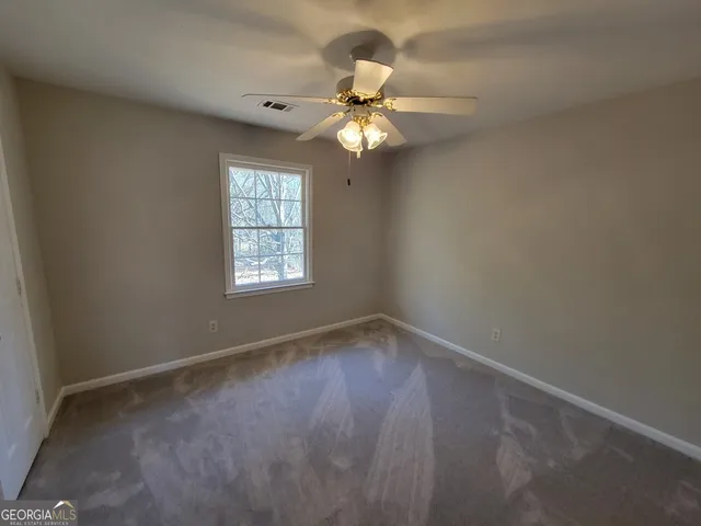 an empty room with a window and a fan