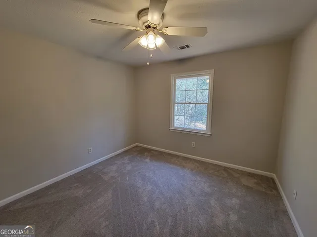 an empty room with windows and fan