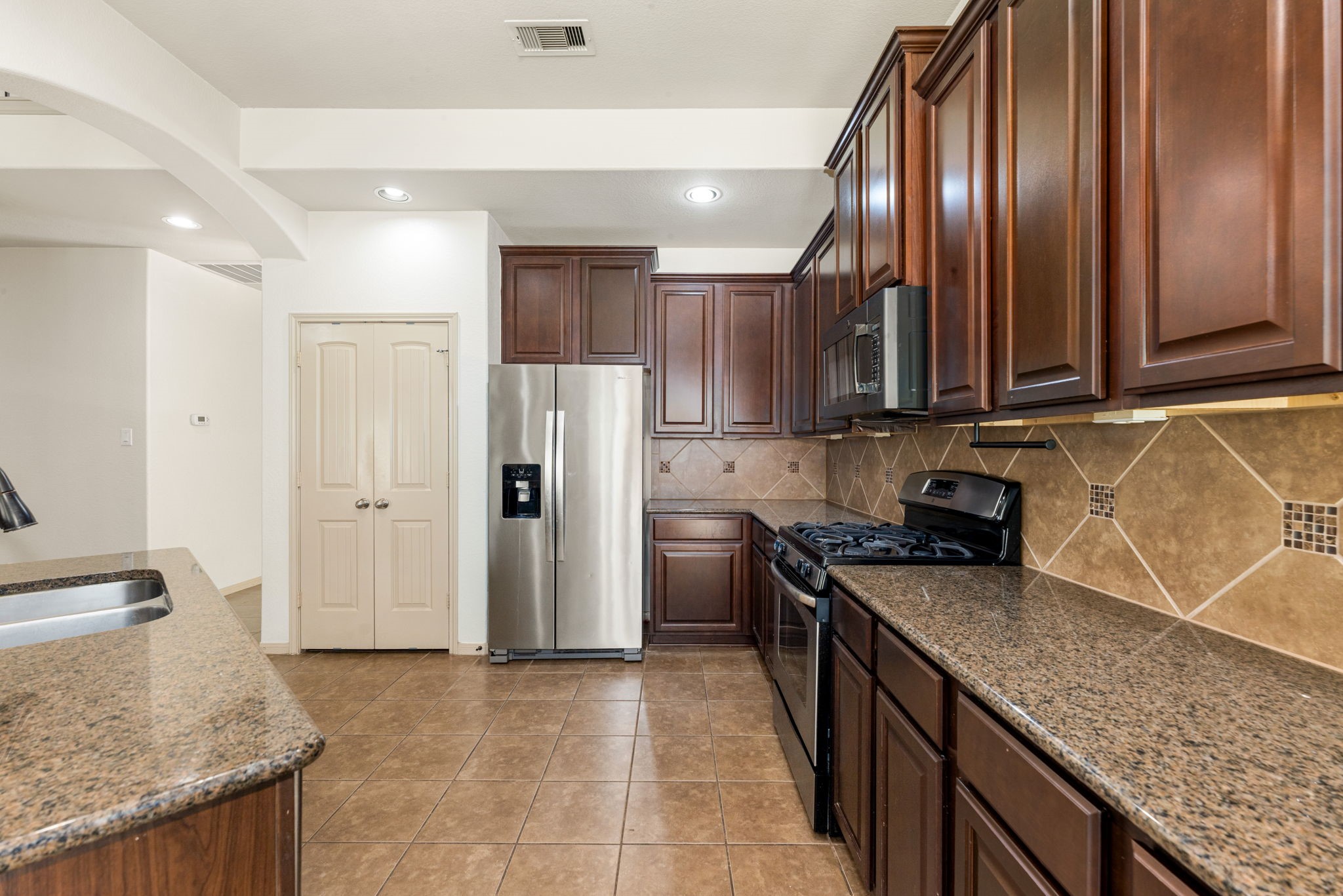 51 Handbridge Place Tomball, TX 77375 - Photo 12 of 46 a kitchen with stainless steel appliances granite countertop a sink stove and refrigerator