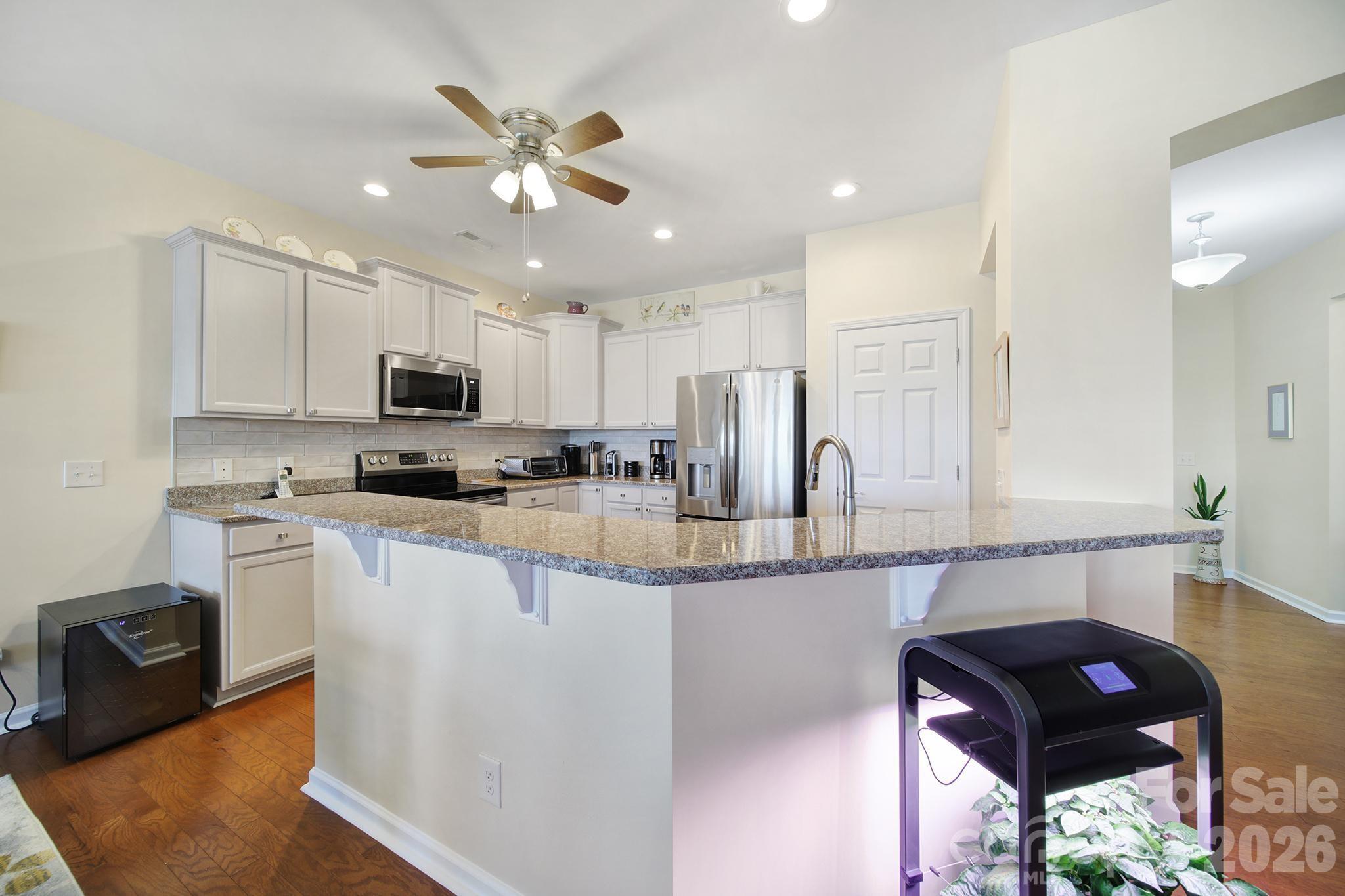 8080 Pawleys Court Fort Mill, SC 29707 - Photo 7 of 44 a kitchen with granite countertop a refrigerator a sink dishwasher a stove and white countertops with wooden floor