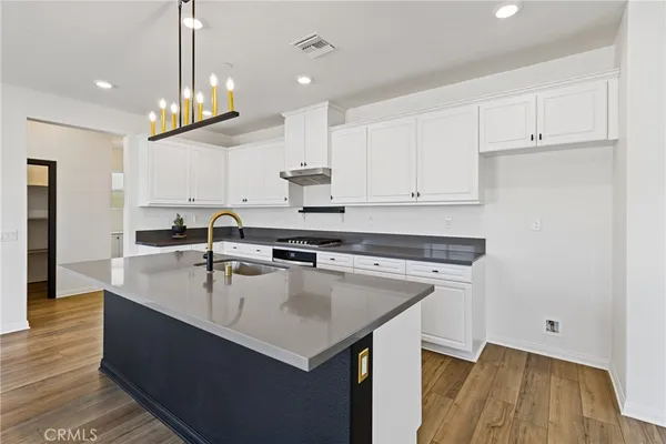 a large kitchen with stainless steel appliances granite countertop a sink dishwasher a stove and a dining table with wooden floor