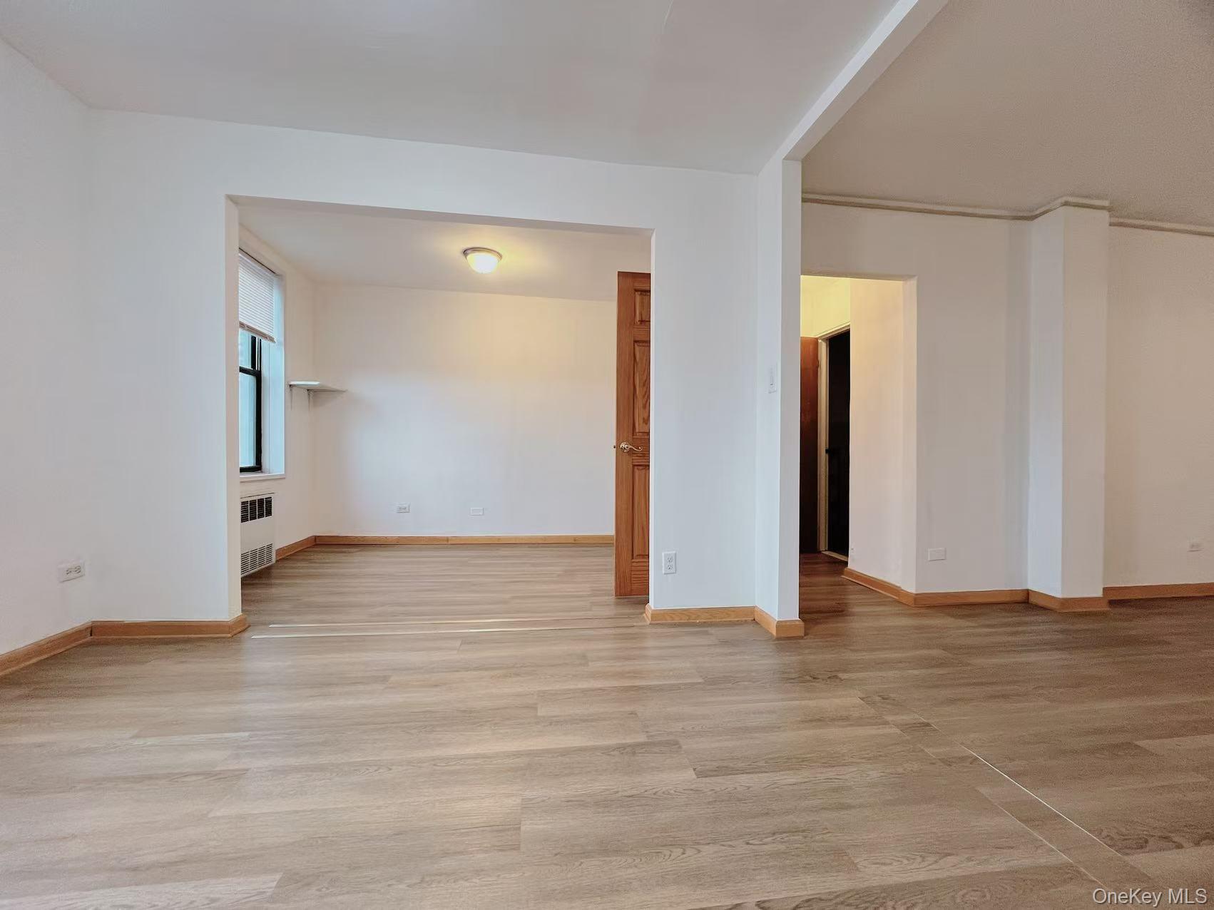 15272 Melbourne Avenue, Unit 3A Queens, NY 11367 - Photo 6 of 13 a view of an empty room with wooden floor and a window