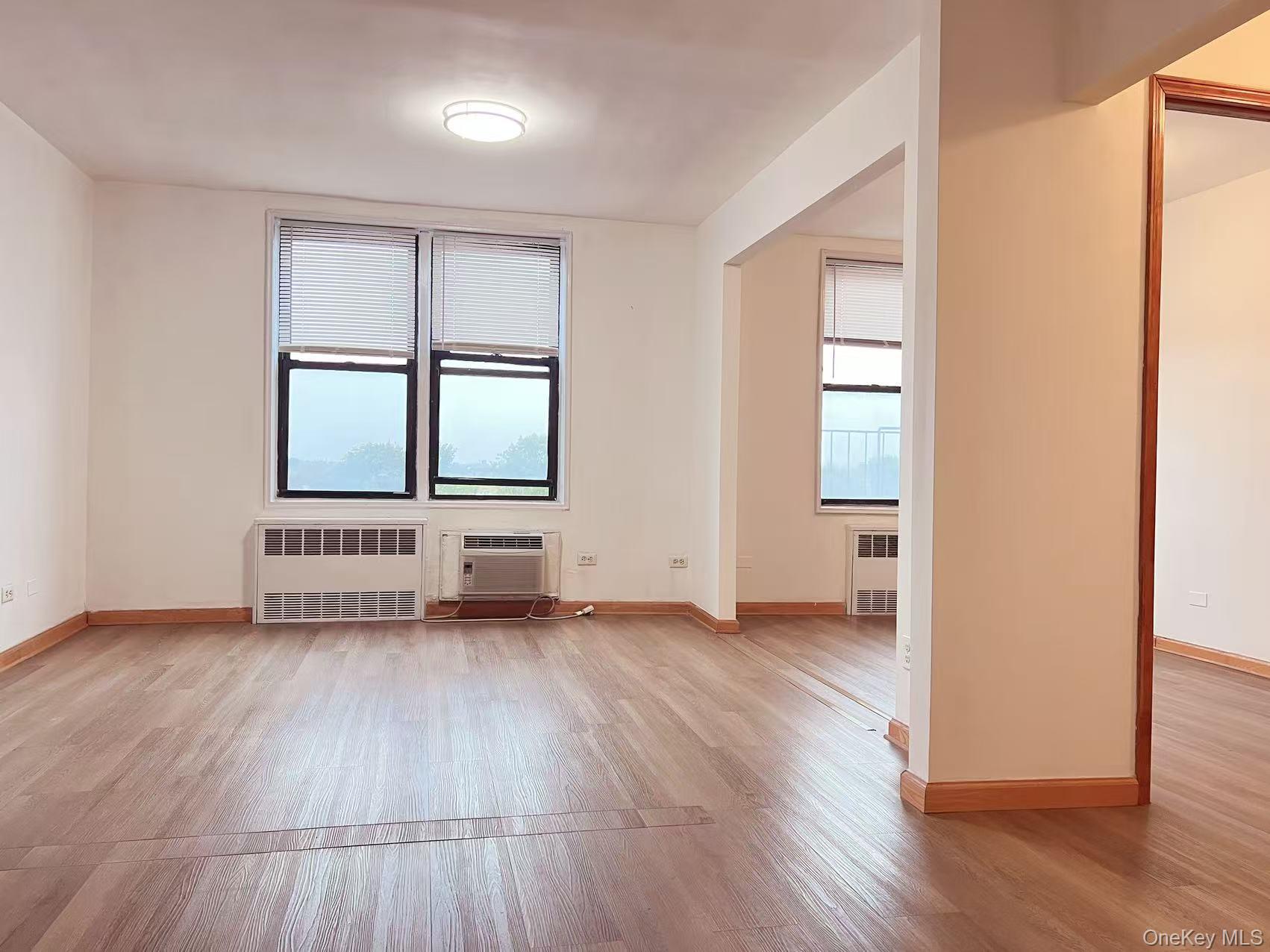 15272 Melbourne Avenue, Unit 3A Queens, NY 11367 - Photo 7 of 13 an empty room with wooden floor and windows