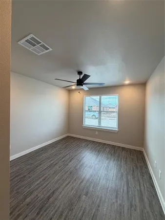 an empty room with wooden floor chandelier fan and windows