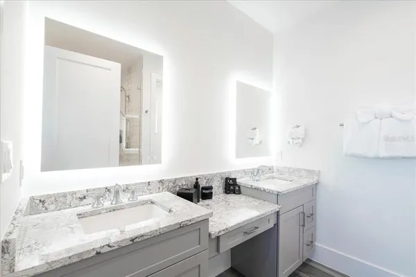 a bathroom with a granite countertop toilet a sink and a mirror