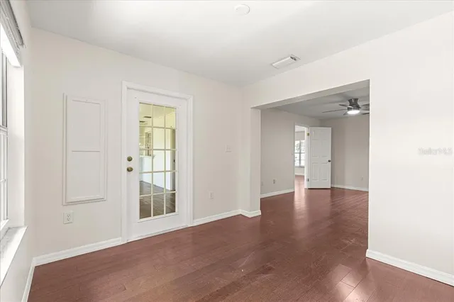 an empty room with wooden floor and ceiling fan