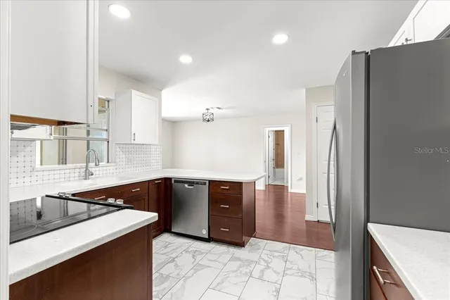 a large kitchen with kitchen island a sink a stove a refrigerator and white cabinets with wooden floor