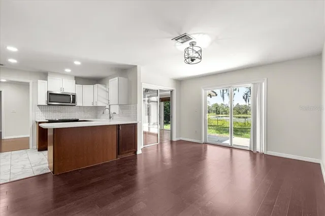 an empty room with wooden floor and large windows