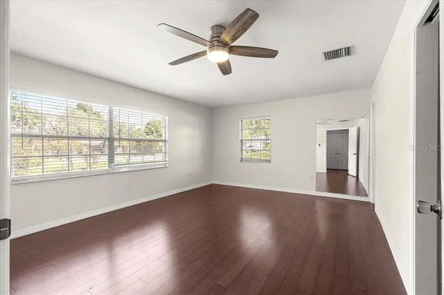 a view of empty room with wooden floor and fan