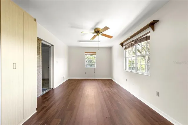 an empty room with wooden floor and windows