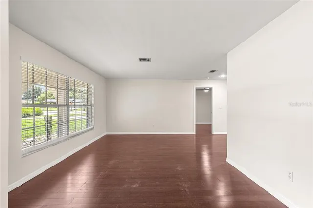 an empty room with wooden floor cabinet and windows