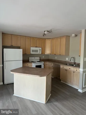a kitchen with kitchen island a stove a sink a refrigerator and cabinets