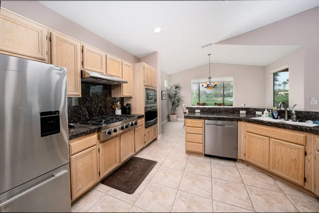 a large kitchen with stainless steel appliances kitchen island granite countertop a refrigerator and a sink