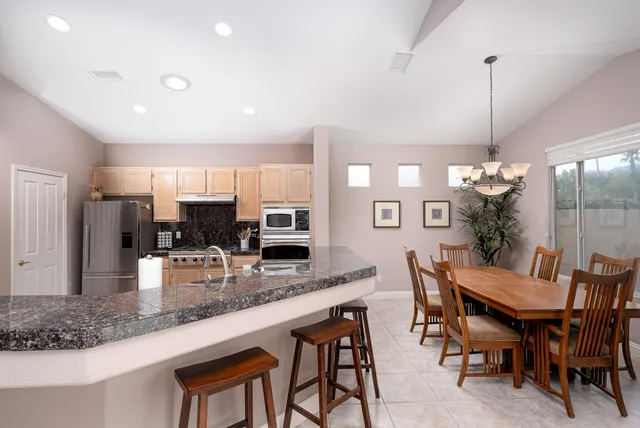 a kitchen with stainless steel appliances granite countertop a dining table chairs and granite counter tops