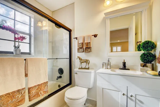 a bathroom with a sink a toilet a mirror and shower