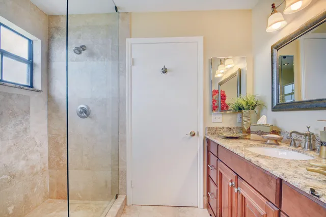 a bathroom with a granite countertop shower sink and mirror