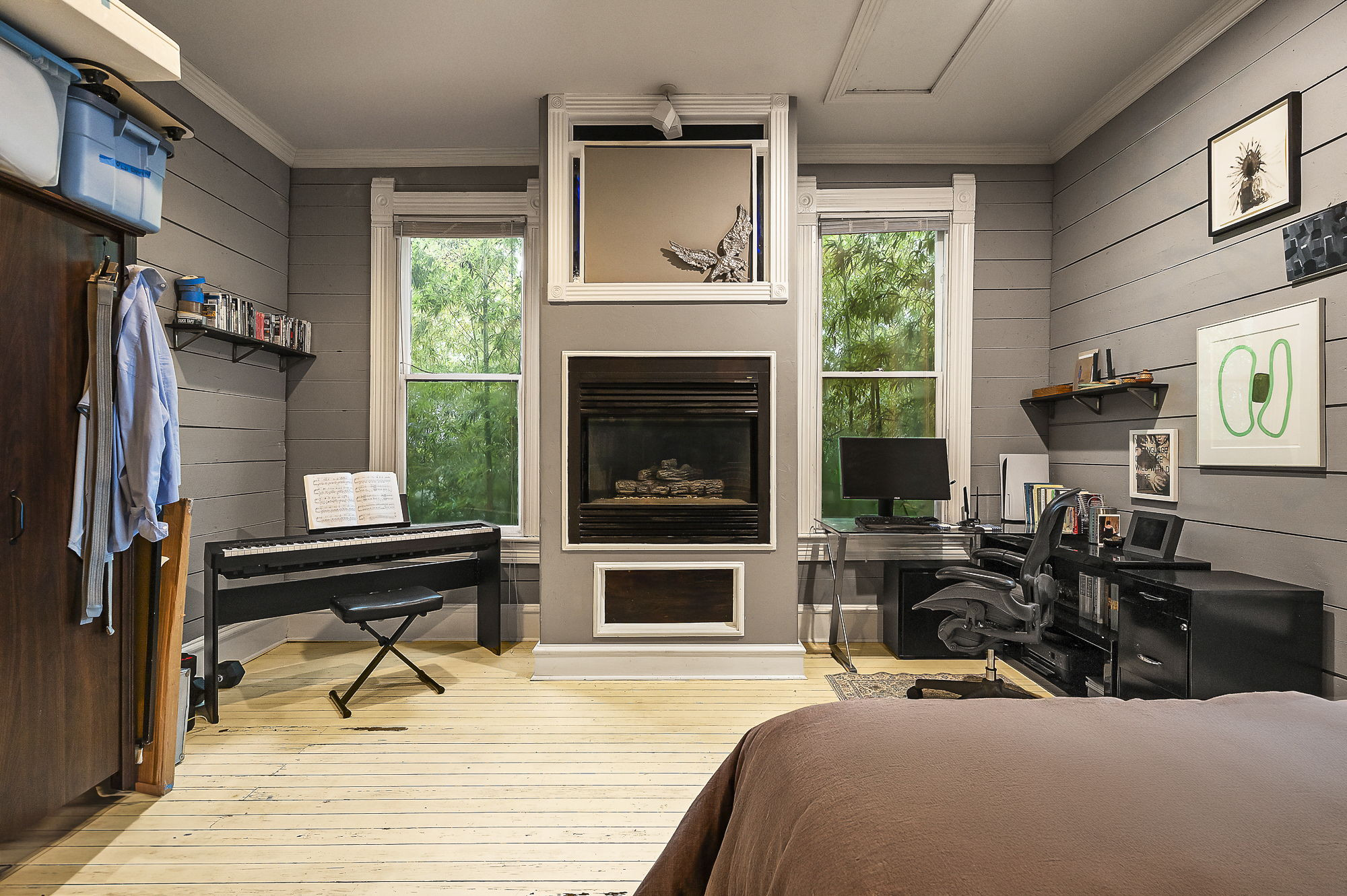 1007 East 8th Street Austin, TX 78702 - Photo 16 of 40 Bedroom with an office area, wood walls, light wood finished floors, a large fireplace, and multiple windows