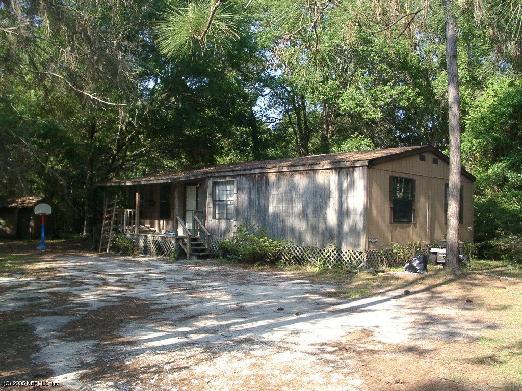 a backyard of a house with table and chairs under an umbrella