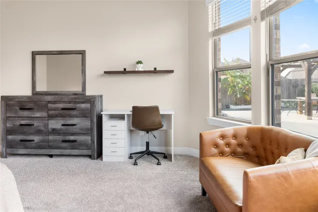 a living room with a large window and a dining table with garden view