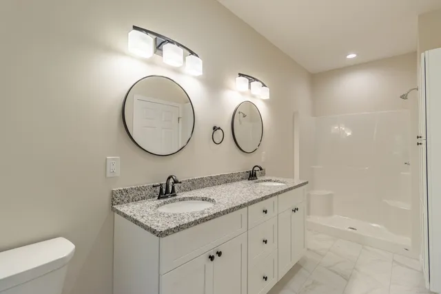 a bathroom with a granite countertop double vanity sink and a mirror