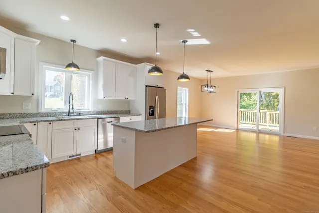 a large kitchen with granite countertop a large center island a sink stainless steel appliances and cabinets