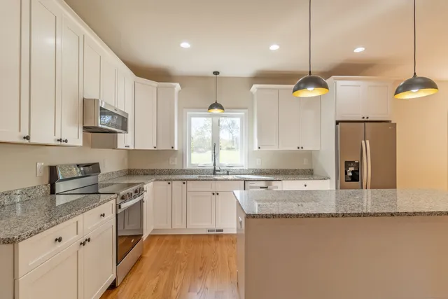 a kitchen with stainless steel appliances granite countertop a sink a stove and a wooden floors