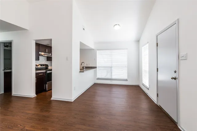 a view of a kitchen and an empty room with closet and a window