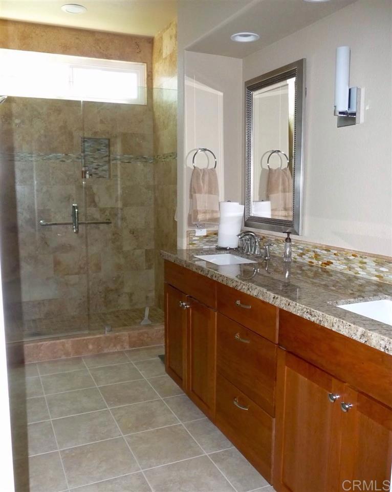 4913 Alicante Way Oceanside, CA 92056 - Photo 21 of 34 a bathroom with a granite countertop sink a mirror and shower