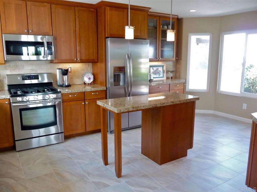 4913 Alicante Way Oceanside, CA 92056 - Photo 9 of 34 a kitchen with stainless steel appliances granite countertop a stove a sink and a microwave