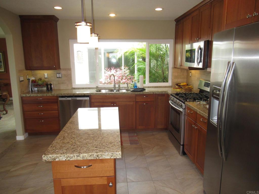 4913 Alicante Way Oceanside, CA 92056 - Photo 10 of 34 a kitchen with stainless steel appliances granite countertop sink stove and refrigerator