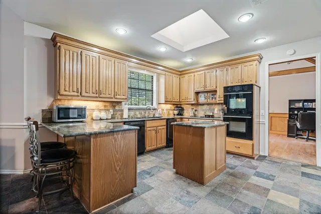 a kitchen with kitchen island granite countertop a stove refrigerator and cabinets
