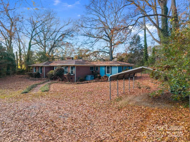 a view of house with outdoor space and trees in the background