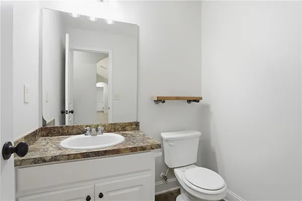 a bathroom with a granite countertop toilet a sink and a mirror
