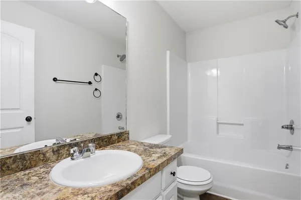 a bathroom with a granite countertop sink a toilet a mirror and shower