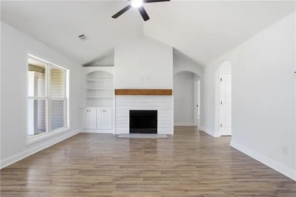 an empty room with windows fireplace and wooden floor