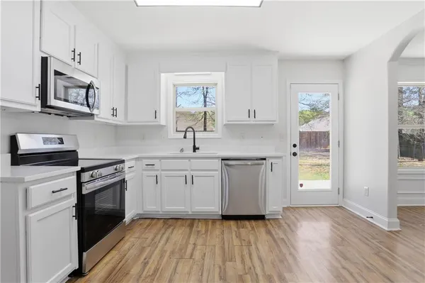 a kitchen with granite countertop a sink cabinets stainless steel appliances and a window