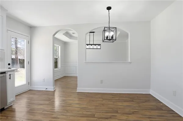 a view of empty room with wooden floor and kitchen view