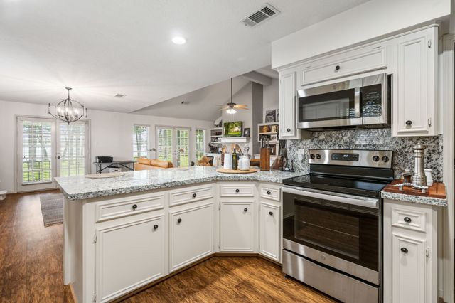 a kitchen with granite countertop a stove a sink and a microwave