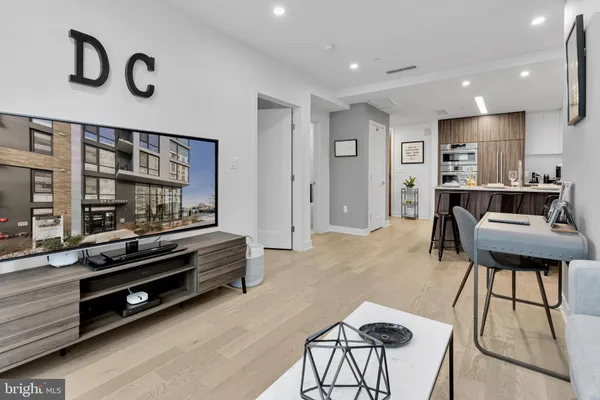 a living room with furniture a flat screen tv and kitchen view