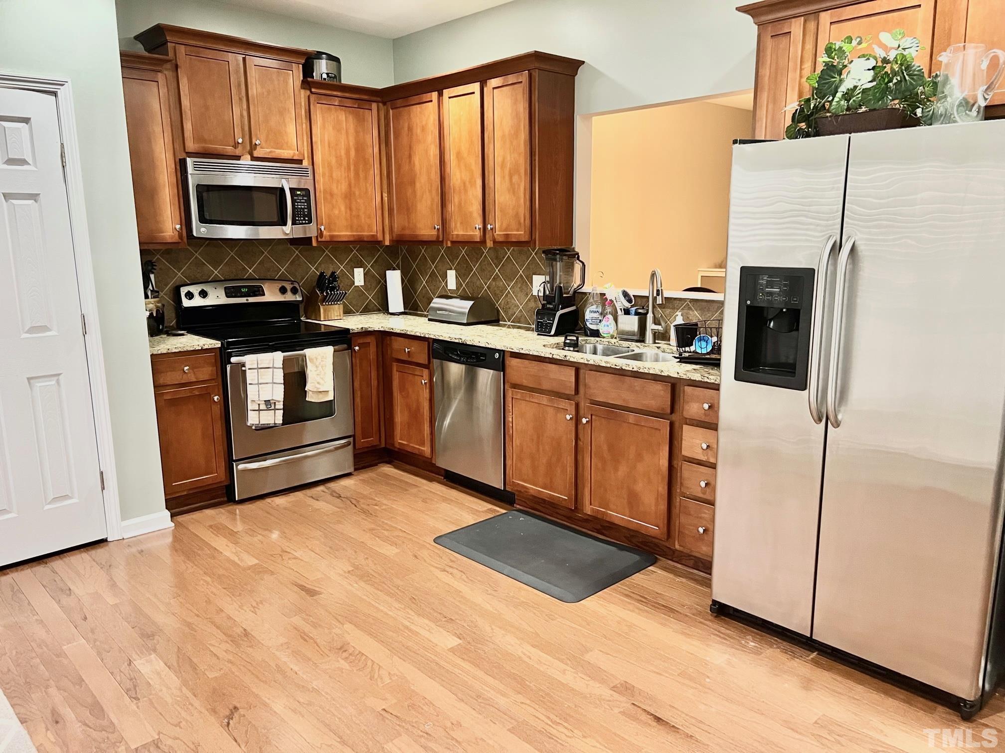 1338 Regulator Street Raleigh, NC 27603 - Photo 8 of 21 a kitchen with stainless steel appliances a stove a microwave and a refrigerator