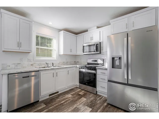 a kitchen with kitchen island granite countertop a refrigerator stove top oven and sink
